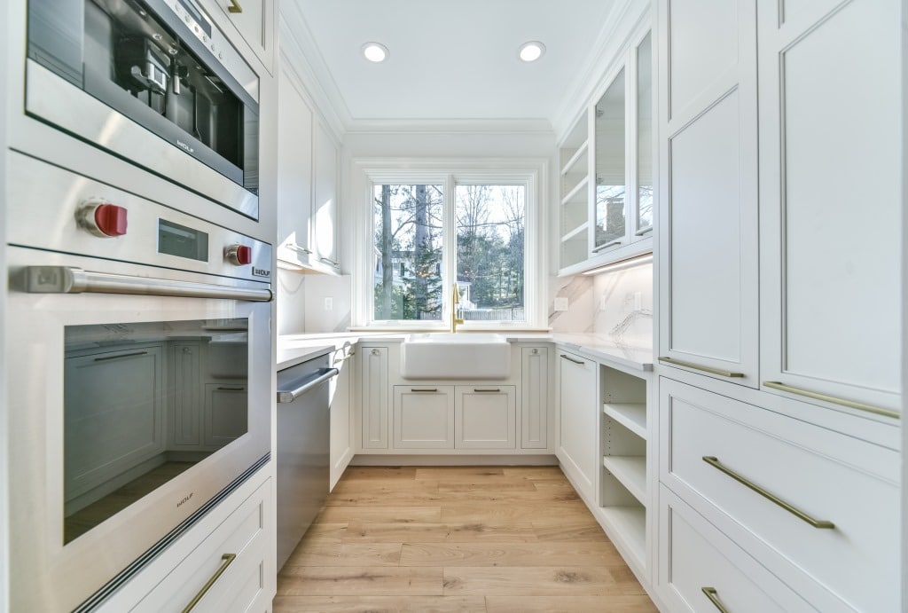 A modern, luxurious kitchen featuring sleek white cabinetry, integrated stainless steel appliances, quartz countertops, and hardwood flooring. The design showcases ample storage and natural light, blending elegance and functionality for a high-value kitchen renovation.